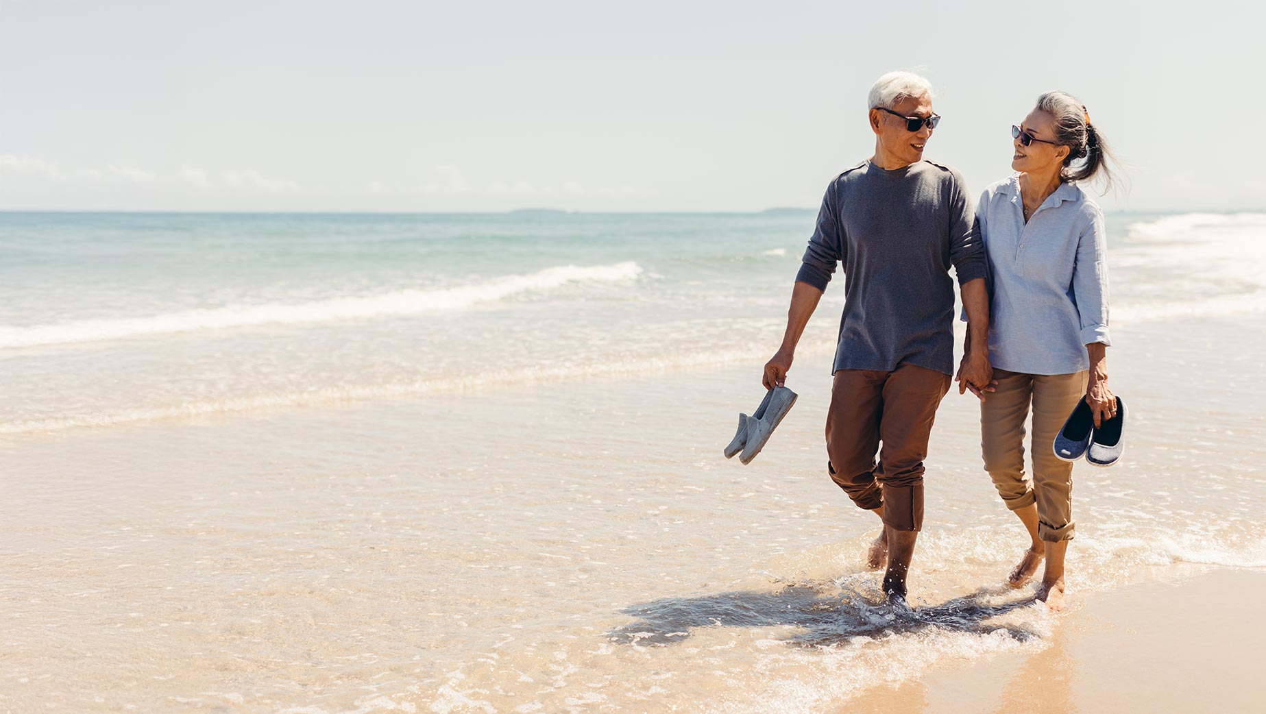 Senior couple walking on the beach, representing Medicare eligibility around age 65
