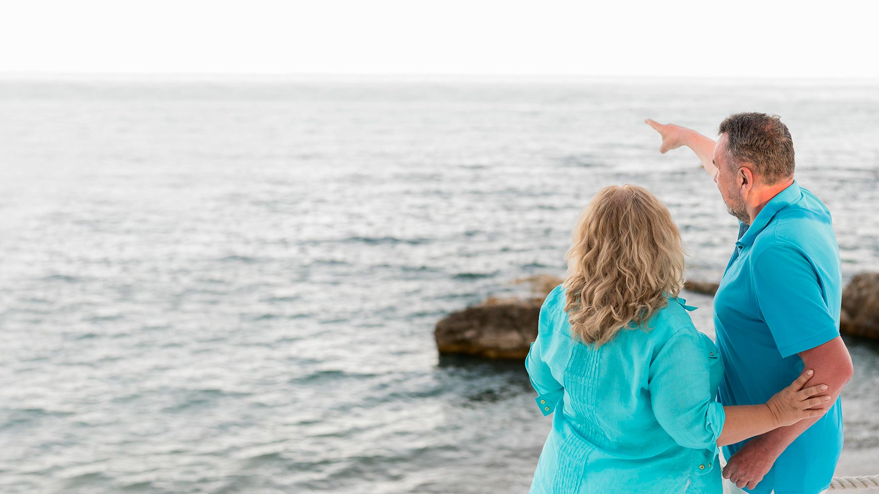 Senior couple walking on the beach, representing Medicare eligibility around age 65